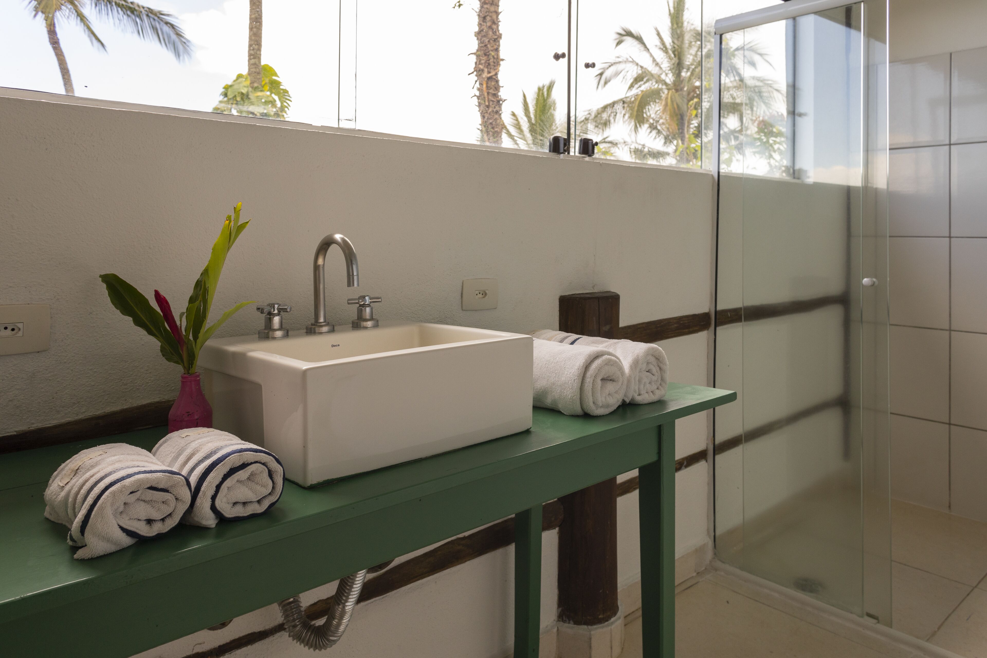 Un baño con lavamanos blanco, tocador verde y cabina de ducha de vidrio.
