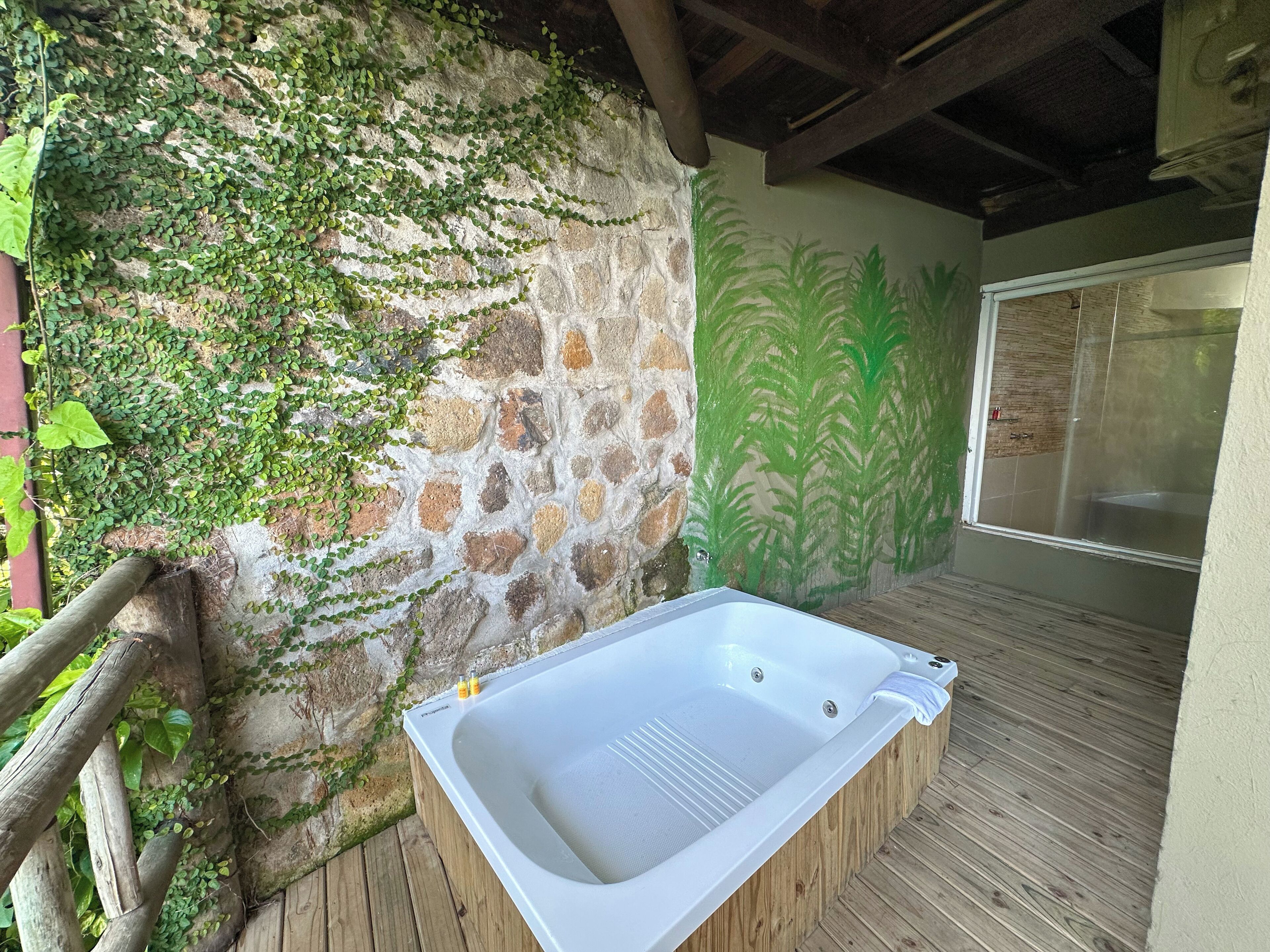 A spa area with a stone wall, wooden deck, and a hot tub.