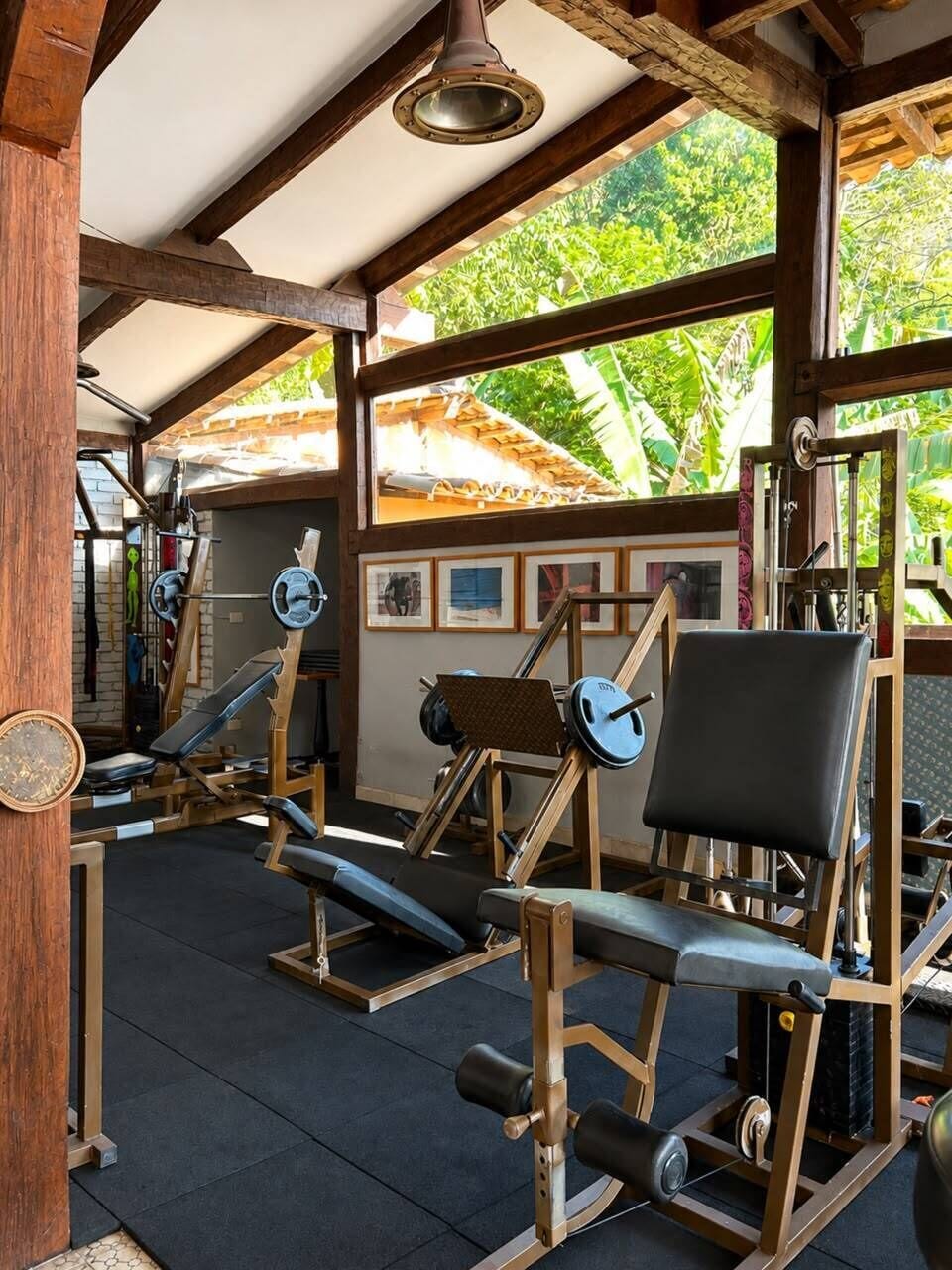 A gym with weightlifting equipment, benches, and a ceiling fan.