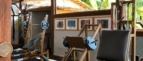 A gym with weightlifting equipment, benches, and a ceiling fan.