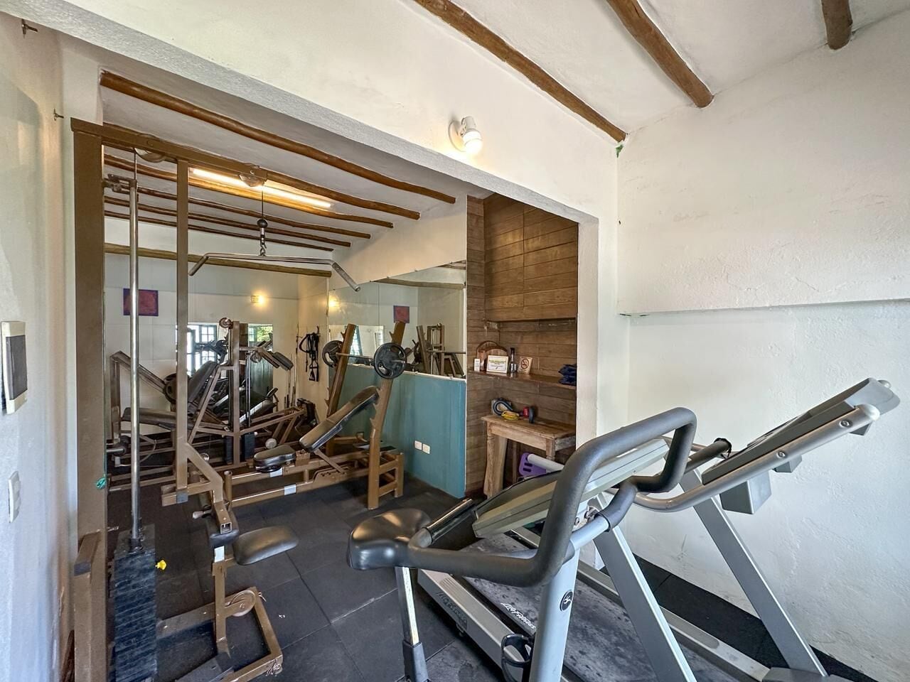 Une salle de sport équipée de divers appareils d’exercice, notamment des tapis de course, des appareils de musculation et des poids libres.