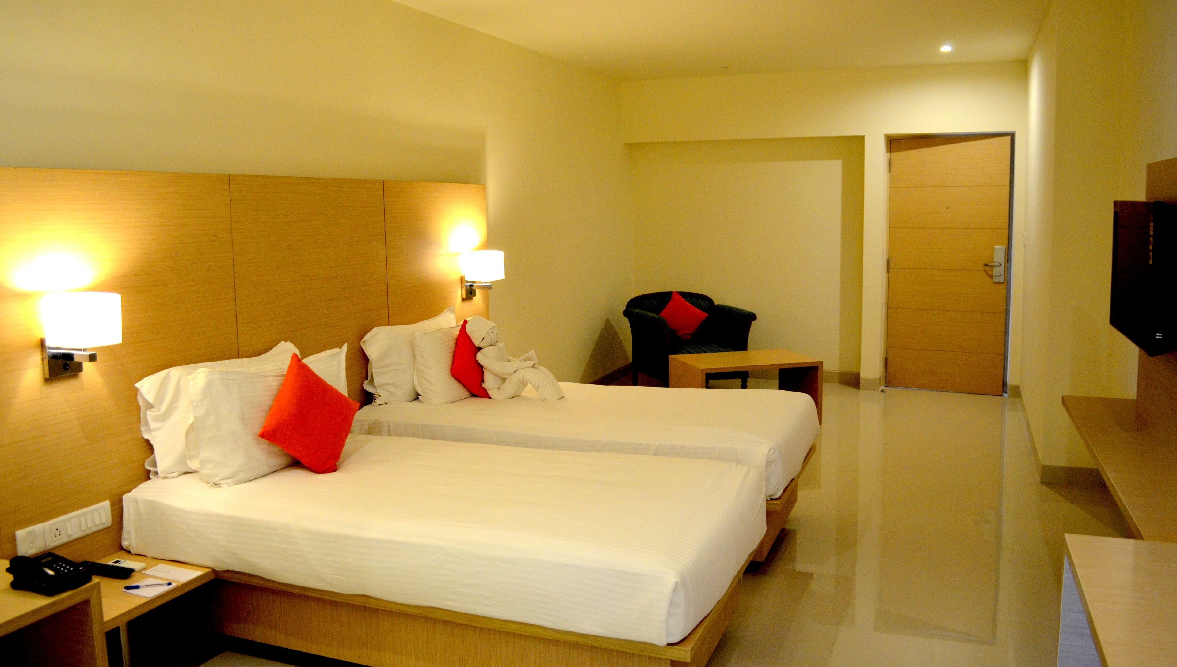 Een hotelkamer met een groot bed, twee nachtkastjes, een stoel, een bureau en een televisie.