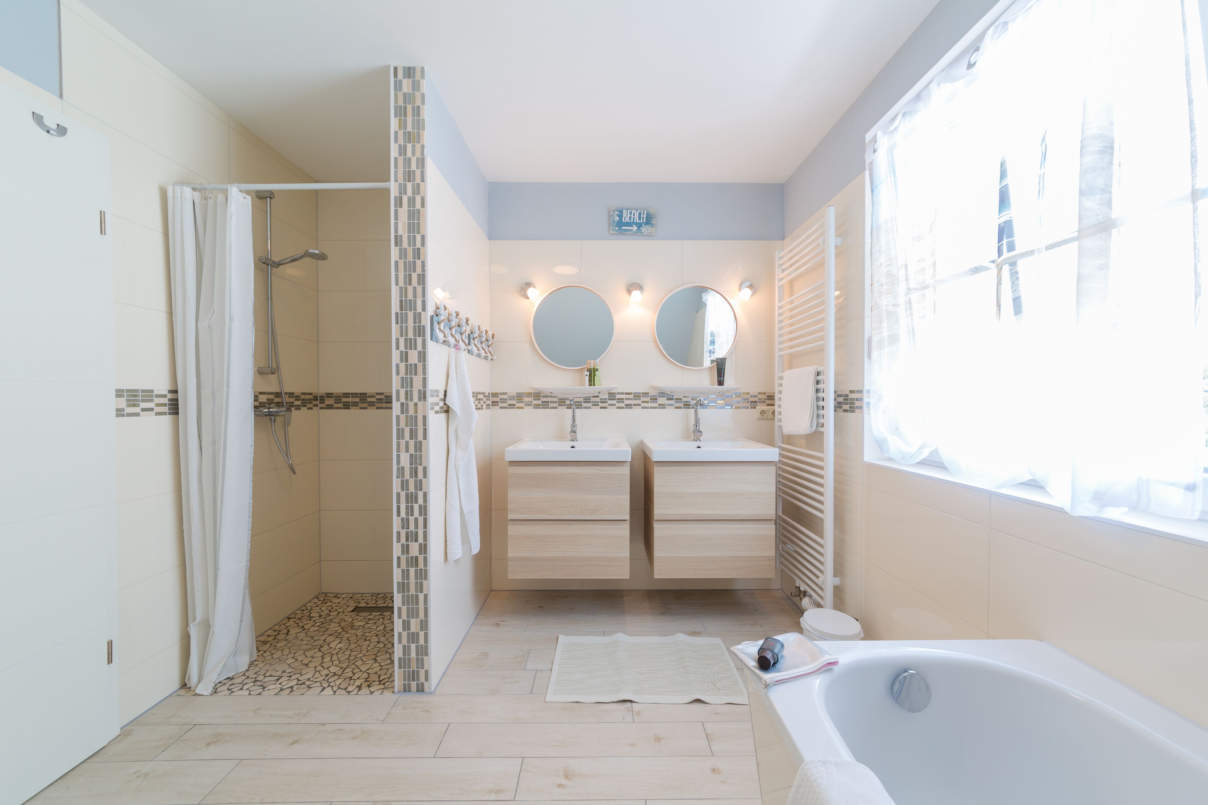 Un baño moderno con ducha, dos lavamanos, bañera y ventana.