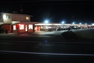 Una estación de servicio de noche con varios coches aparcados.