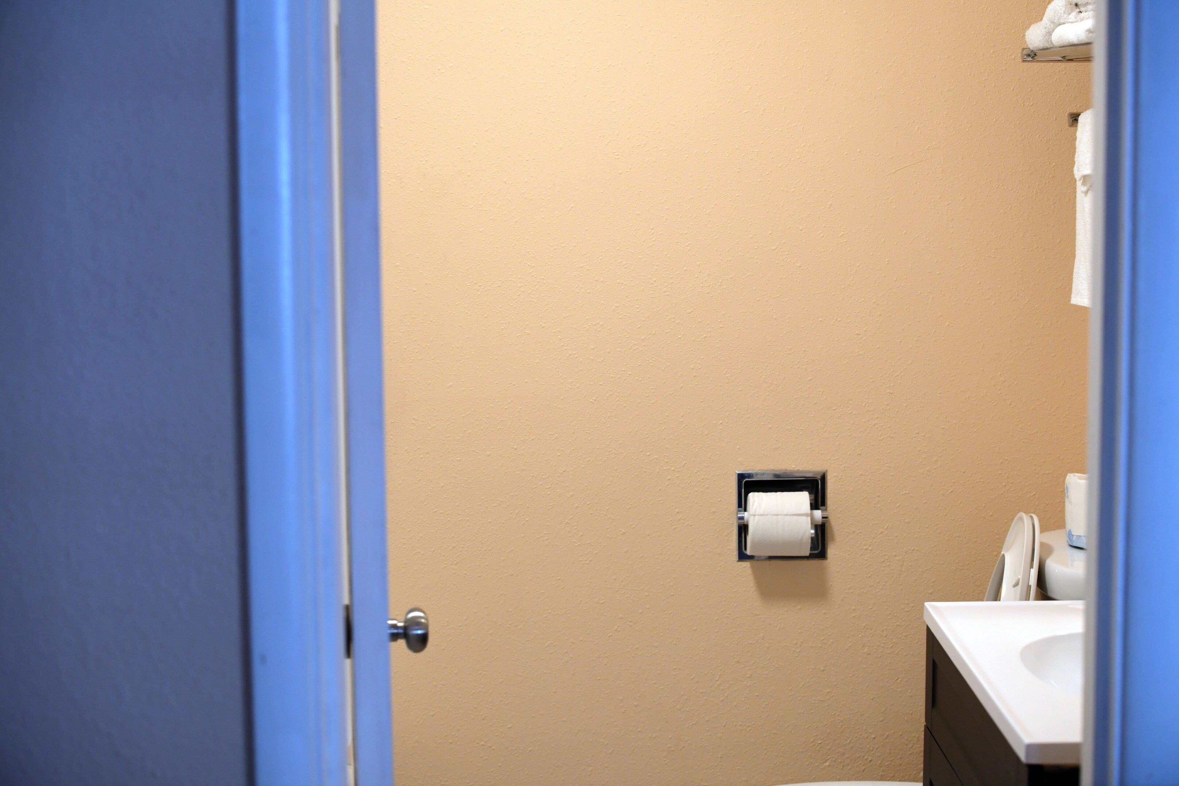 A bathroom with a beige wall, a toilet, a sink, and a towel rack.