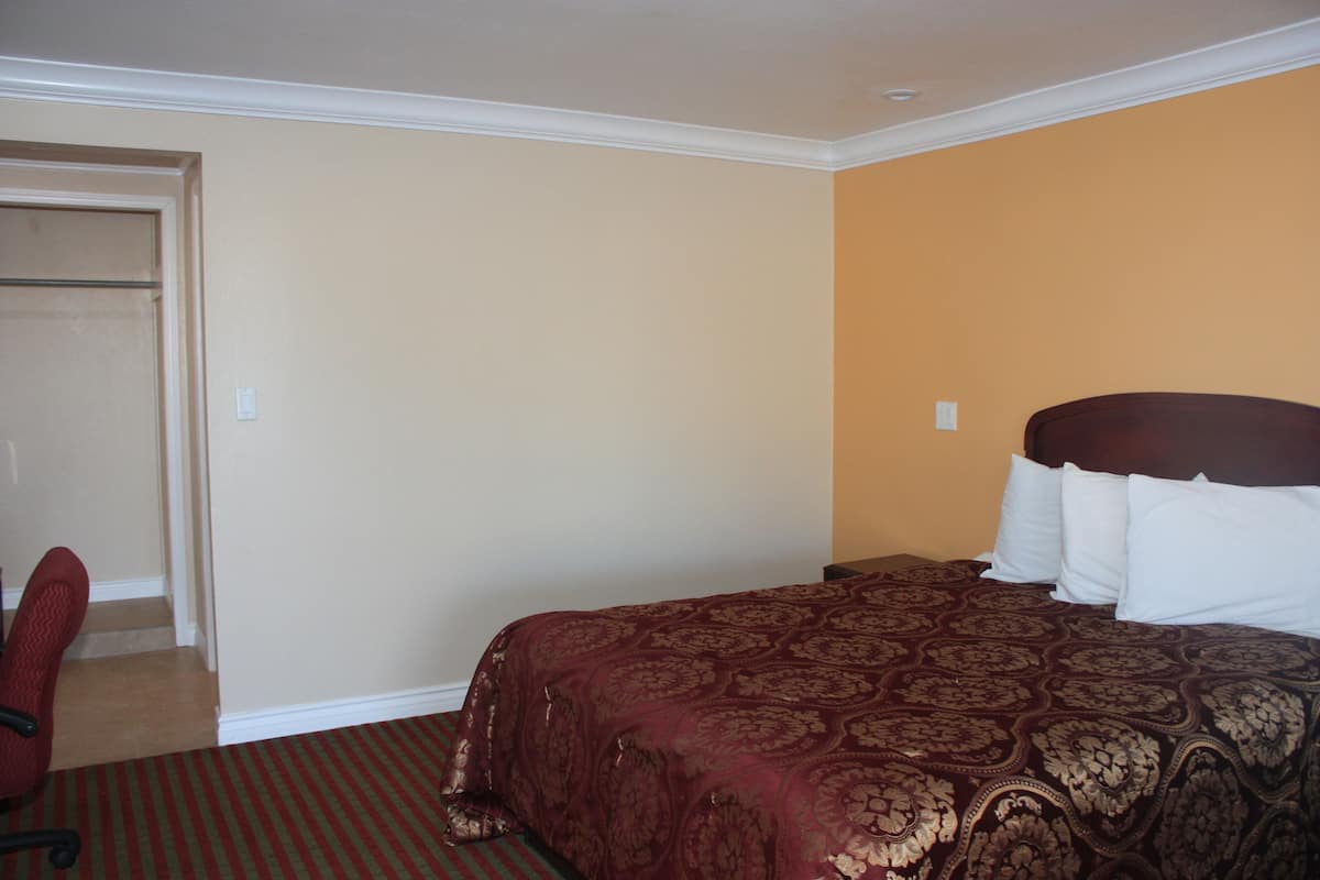 Quarto de hotel com uma cama, uma cadeira e uma porta.