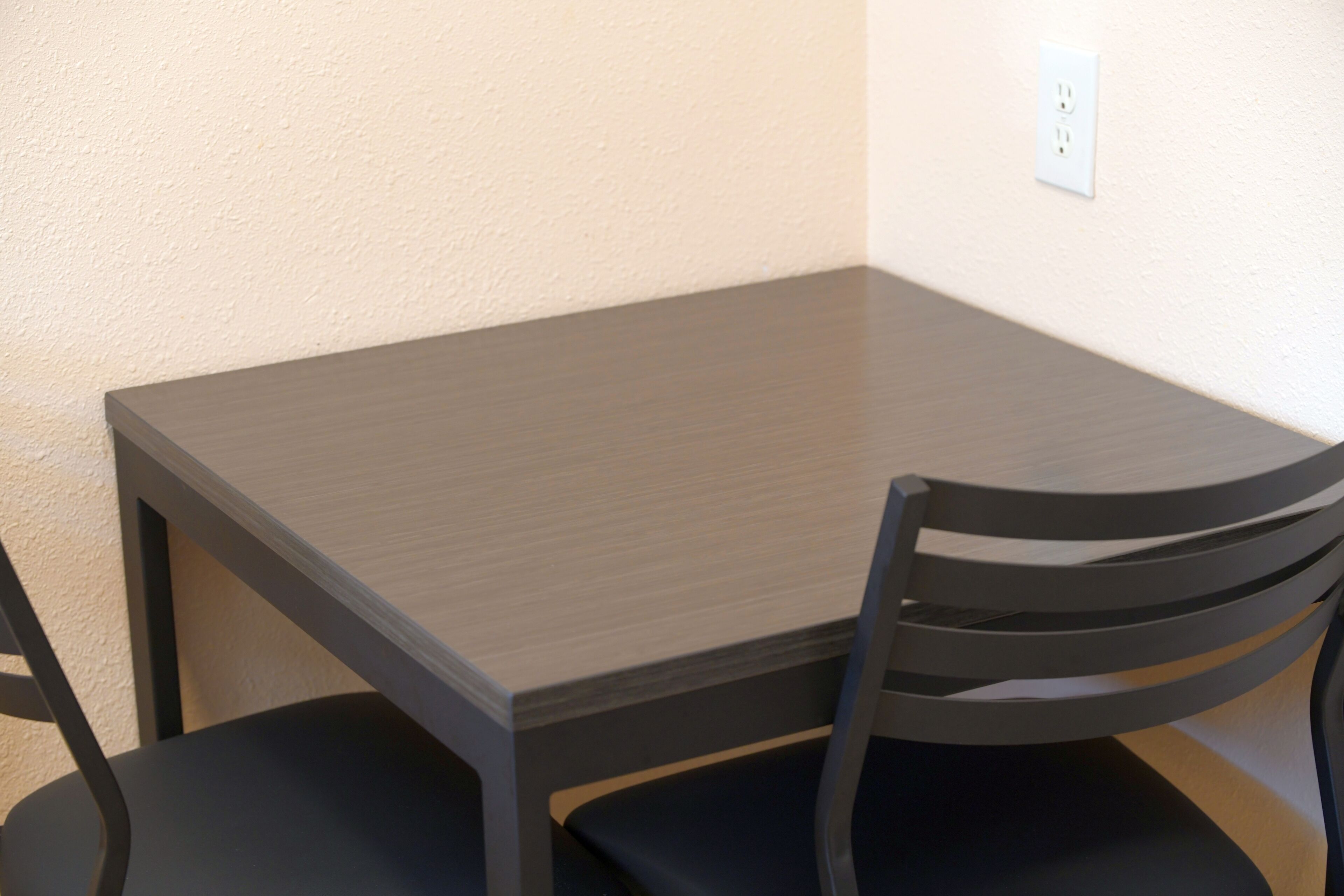 Una pequeña mesa de madera oscura con una sola silla negra.