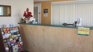 A reception desk with a wooden counter, a mirror above it, and a bulletin board with various items.