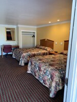Habitación de hotel con dos camas, un escritorio, una silla y un espejo.