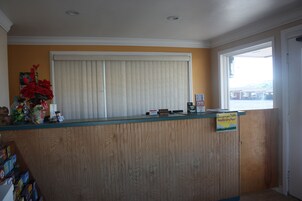 Una recepción con un panel de madera, un tablón de anuncios y una ventana con persianas.