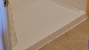 A bathroom with a white tiled shower enclosure and a white bathtub.