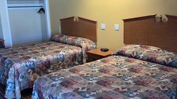 Habitación de hotel con dos camas, un cabecero de madera, una mesita de noche de madera y un armario con espejo.