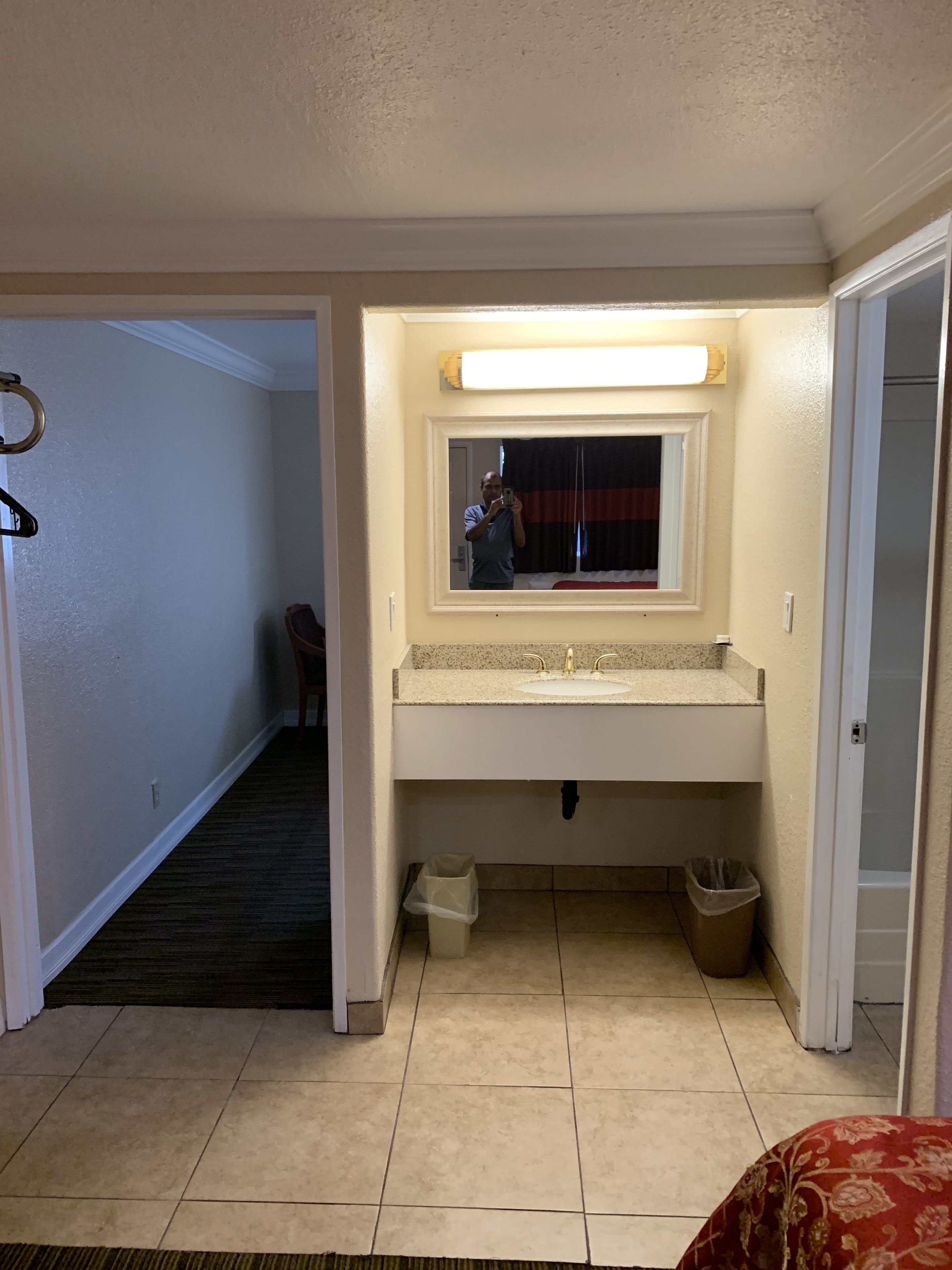 A hotel bathroom with a large mirror, a sink, and a toilet.