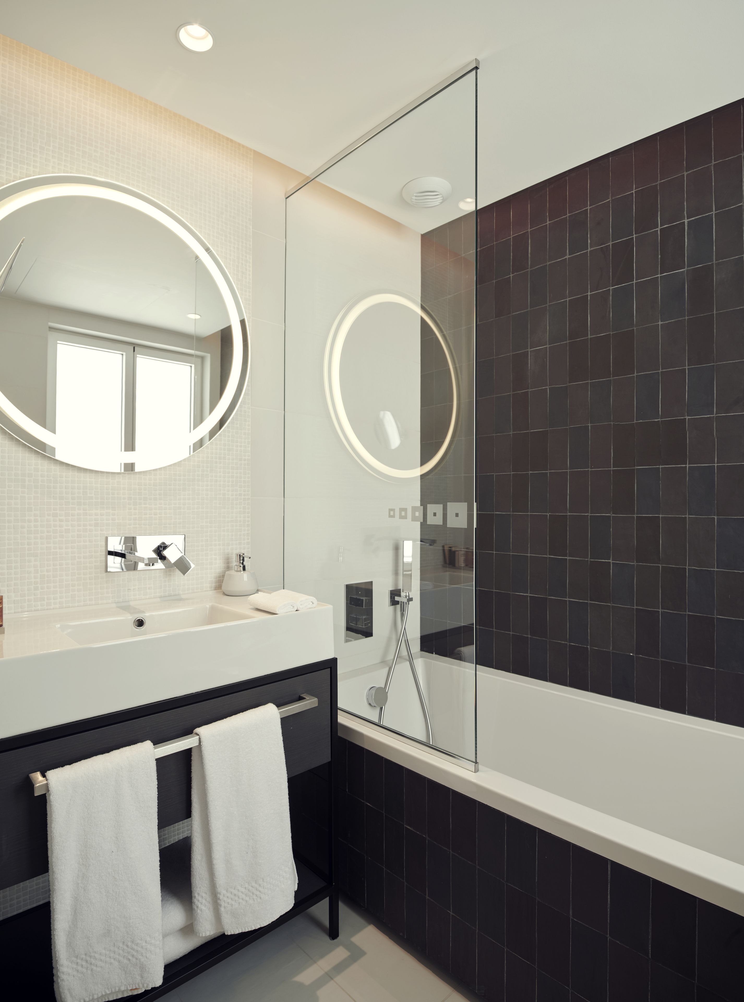 Un baño moderno con un espejo grande, una bañera y una ducha.
