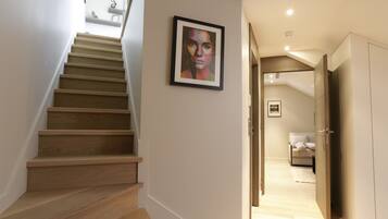 A staircase leading to a bedroom with a bed, a wardrobe, and a framed artwork on the wall.