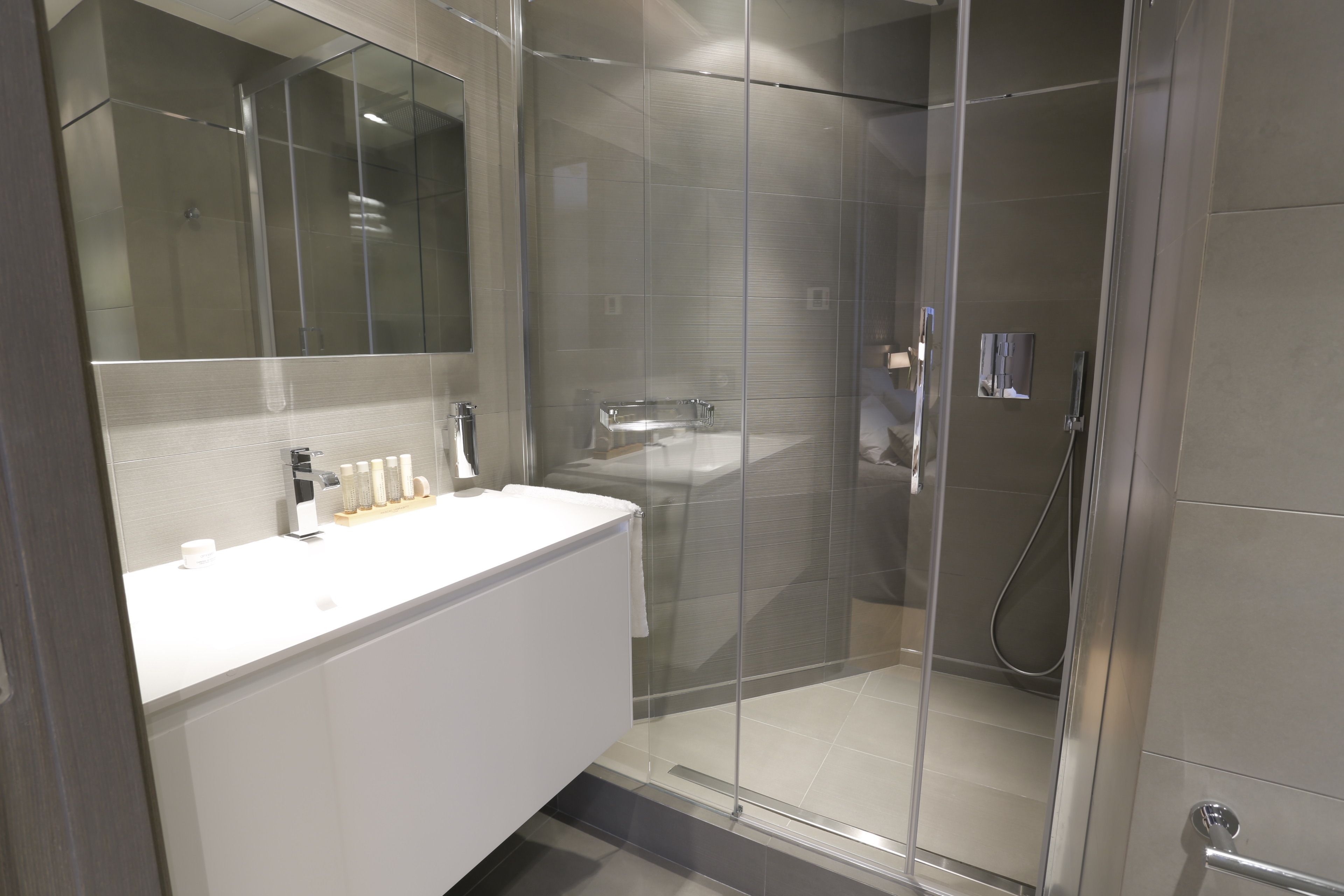 Un bagno moderno con cabina doccia in vetro, un mobile lavabo bianco e uno specchio grande.