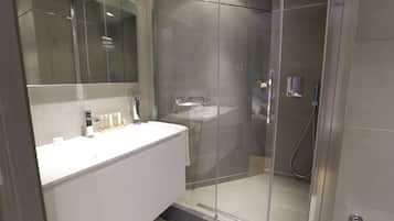 Un bagno moderno con cabina doccia in vetro, un mobile lavabo bianco e uno specchio grande.