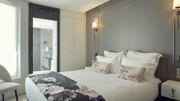 A hotel room with a bed, a chair, a nightstand, and a wall-mounted light fixture.