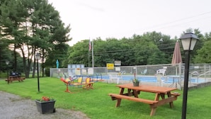 A picnic table, playground equipment, and a swimming pool within a fenced area. - Four Seasons Motel (Catskill)