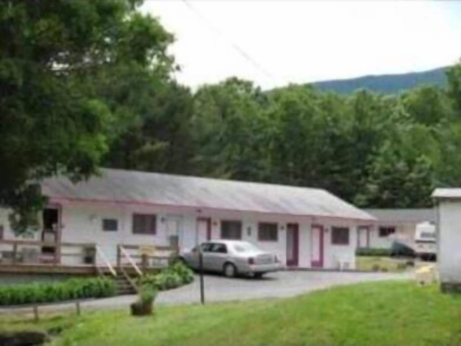 A single-story motel with a red and white exterior, a covered parking area, and a small front yard.