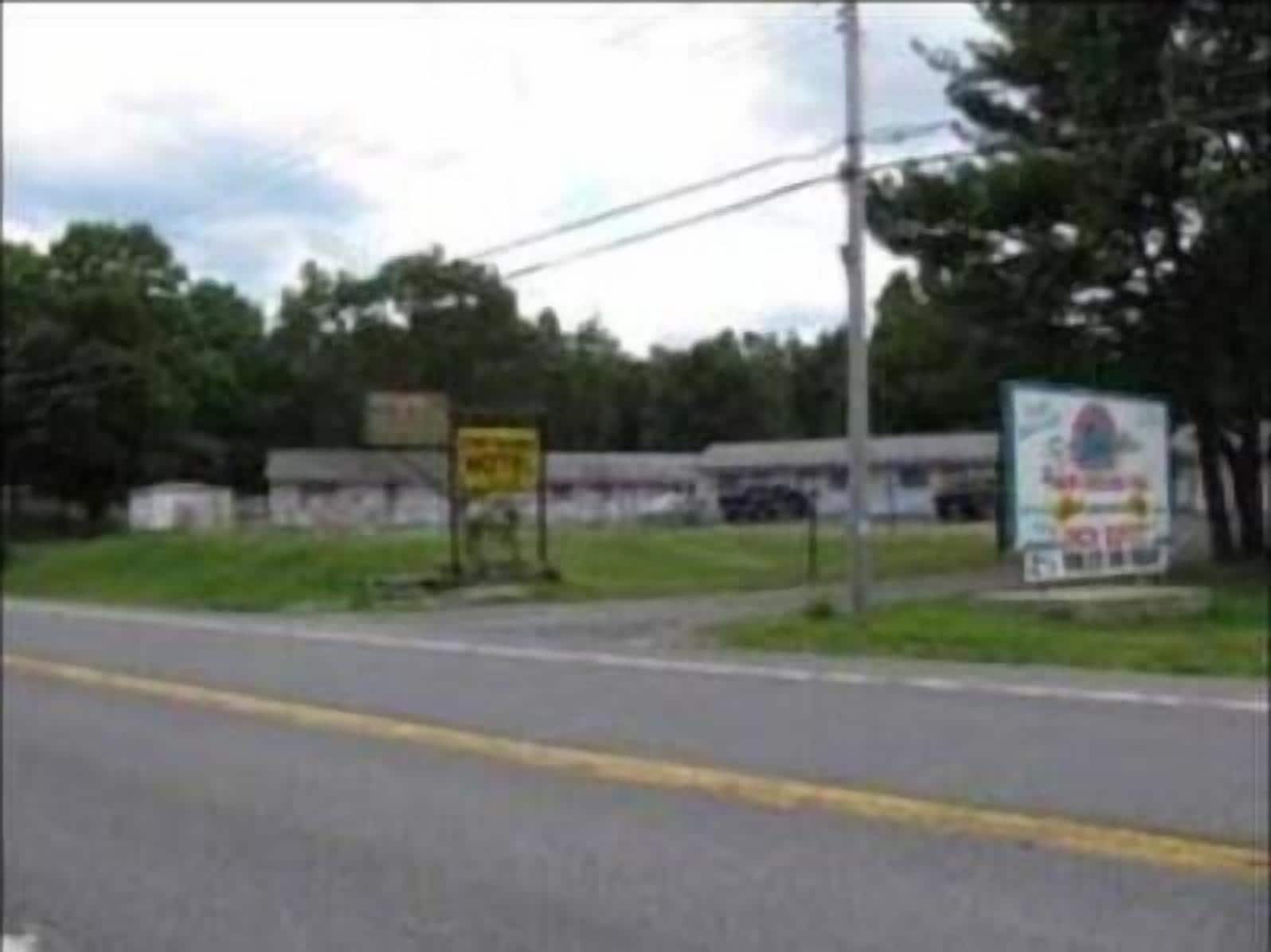 A road with a yellow sign and a billboard.