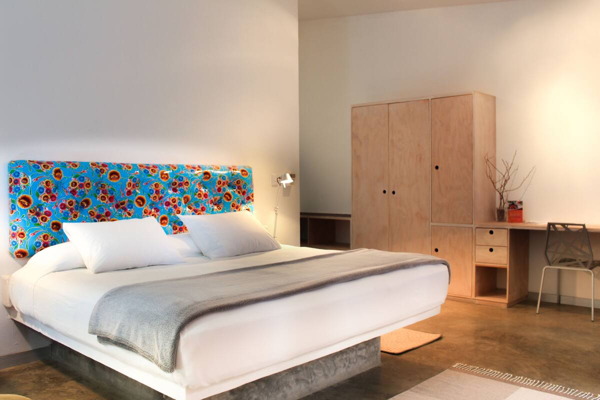 Un dormitorio con una cama, un armario de madera, un escritorio y una silla.