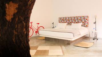 Camera da letto con un letto, una testata fiorata, una bicicletta rossa e il tronco di un albero in primo piano.