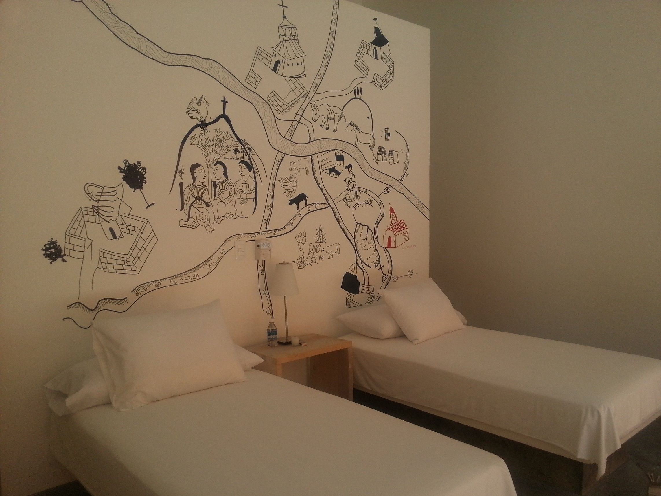 Ein Zimmer mit zwei Betten, einem Nachttisch und einer Wand mit Wandgemälde.