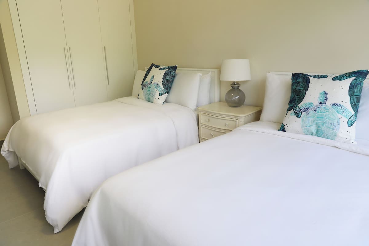Een hotelkamer met twee enkele bedden, een nachtkastje met een lamp en een kledingkast.