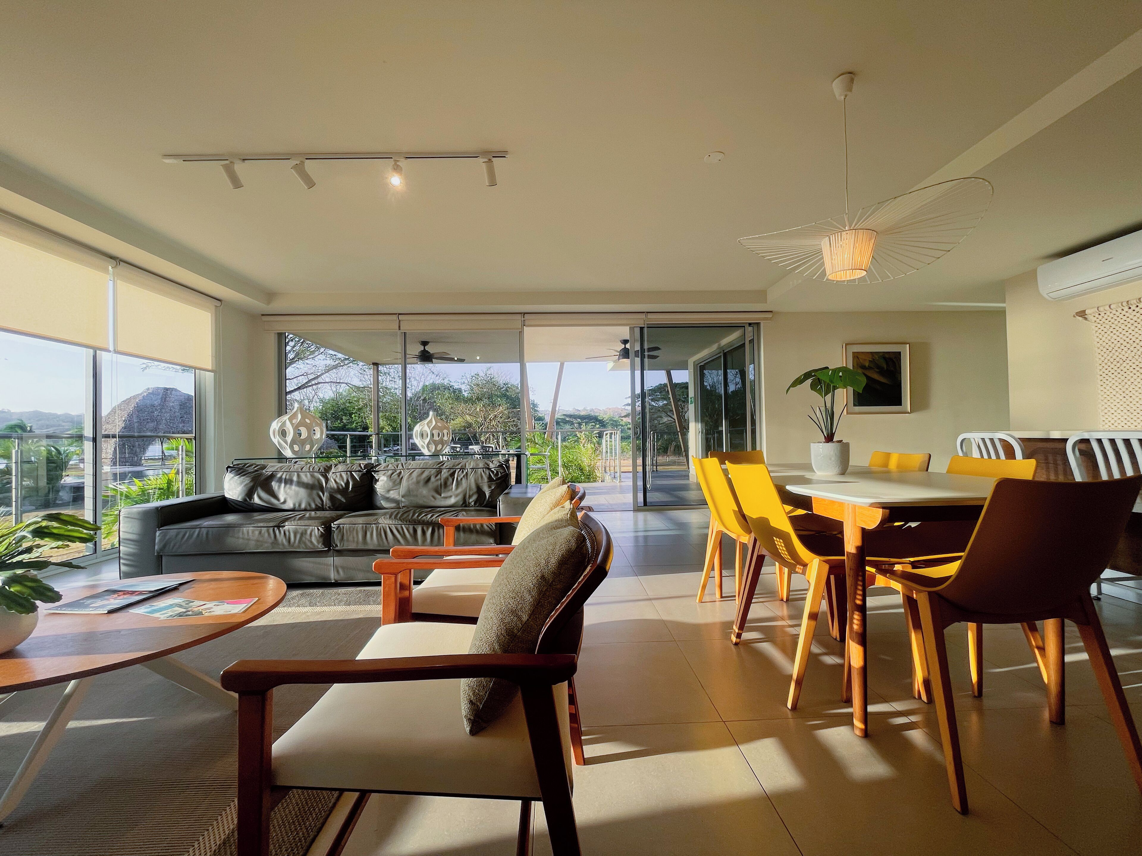 A spacious living area with a sofa, chairs, a dining table, and a view of the outdoors.