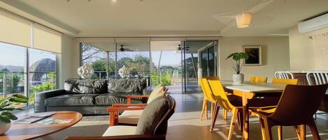 A spacious living area with a sofa, chairs, a dining table, and a view of the outdoors.