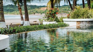 Ein klares Schwimmbecken mit Blick auf den Strand und Palmen.