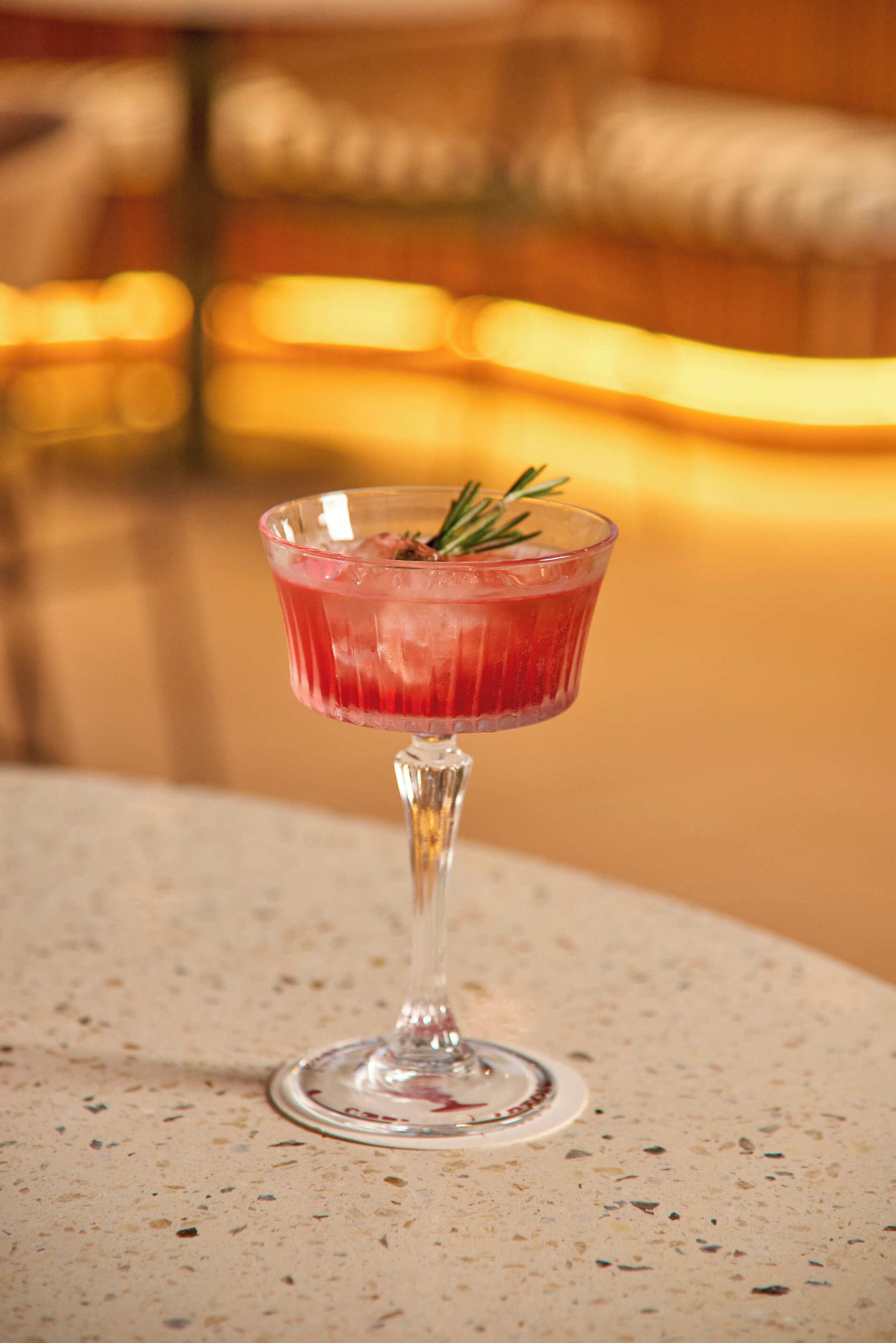 A cocktail in a glass with a stem, placed on a speckled surface.