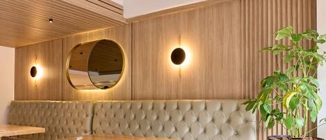 Un comedor moderno con techo de madera, un espejo redondo y una planta en maceta.