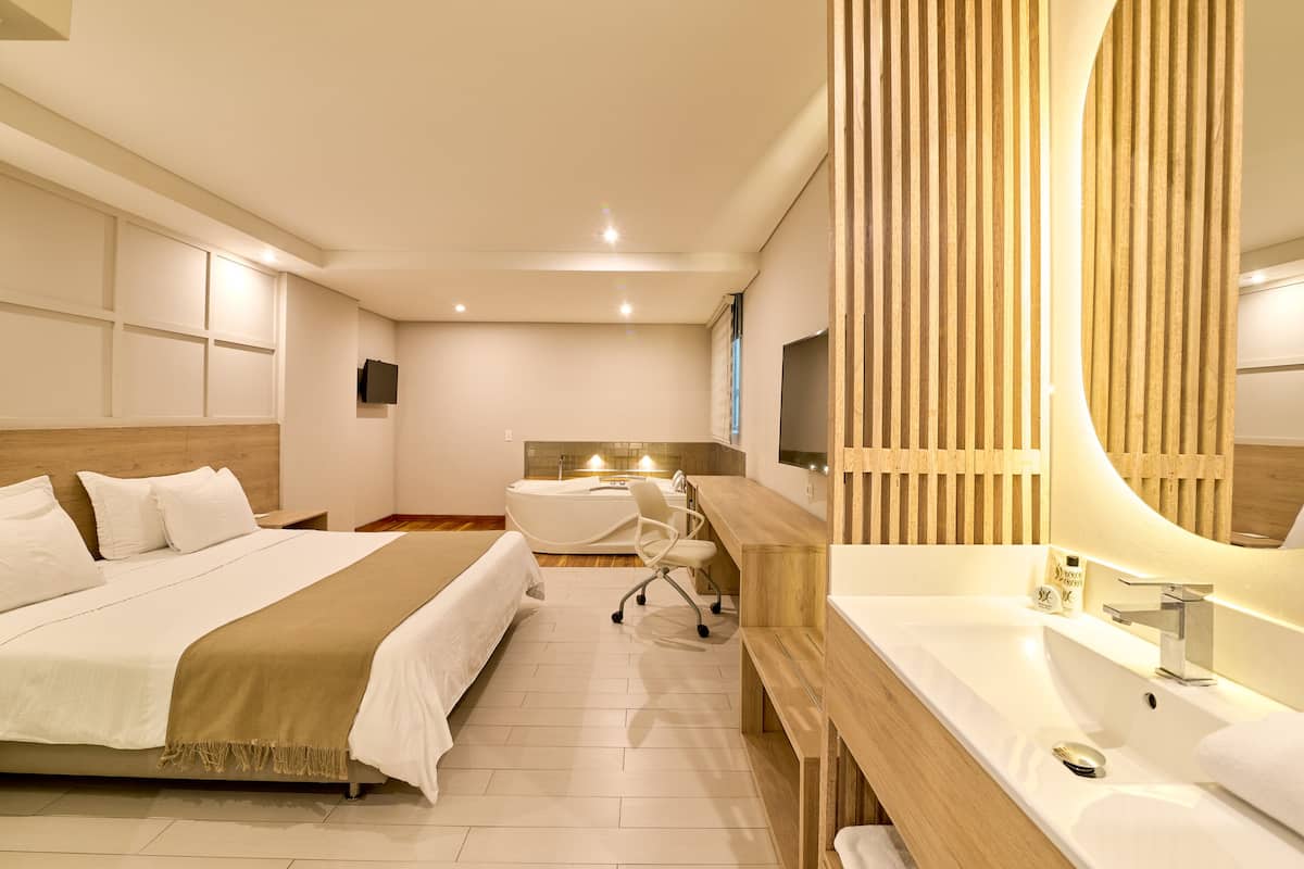 Une chambre d’hôtel moderne, dotée d’un grand lit, d’un bureau et d’une salle de bain avec un meuble-lavabo en bois.