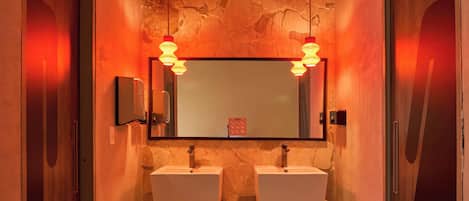 A modern bathroom with two sinks, a large mirror, and wooden doors labeled "WC".