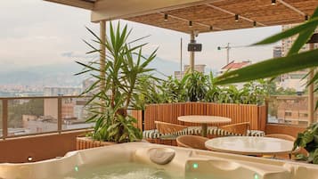 A hot tub area with a view of the city, wooden seating, and potted plants.