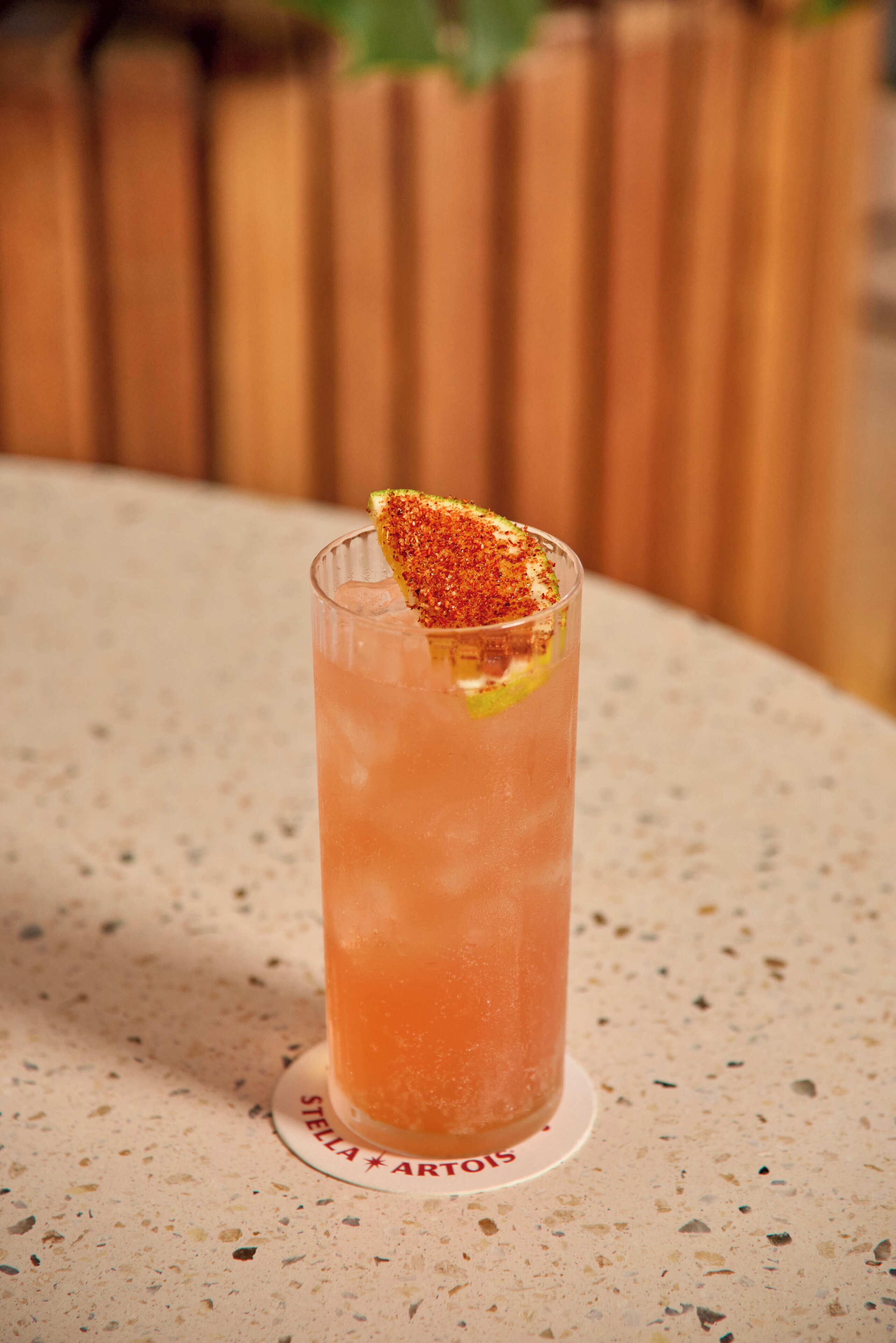 A tall glass with a citrus garnish on a speckled countertop.