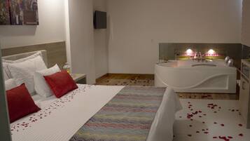 Una habitación de hotel con una cama, un ventanal grande, una bañera y un televisor en la pared.