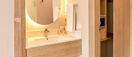 A modern bathroom with a wooden vanity, a large mirror, and a built-in storage closet.
