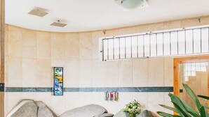 Un área de spa con un banco de piedra, una planta pequeña y una puerta de madera.