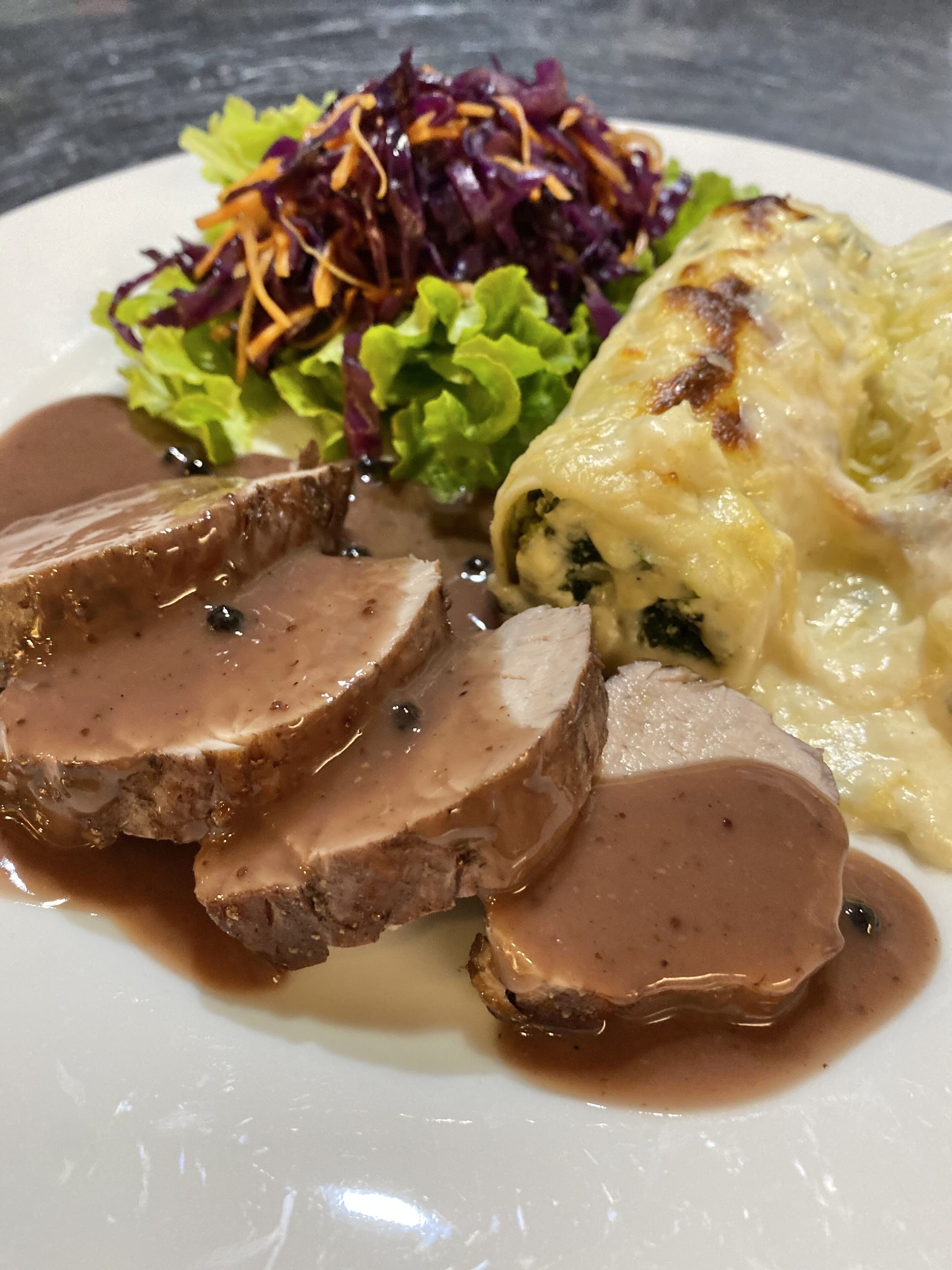 A plate with sliced roast beef, a side of red cabbage, and a baked potato.