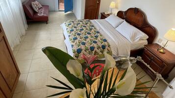 A bedroom with a bed, bedside table, lamp, and a vase with flowers.
