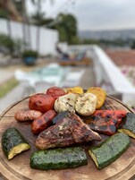 A variety of grilled vegetables and meats on a wooden board.