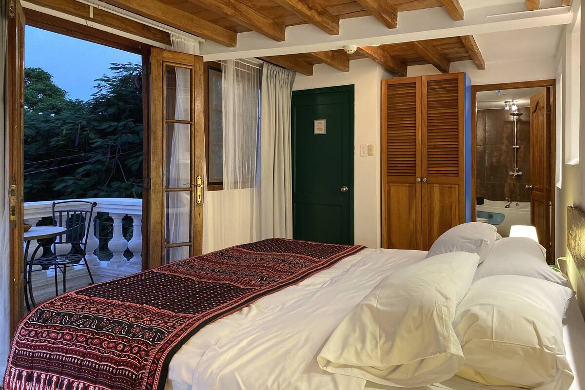 Un dormitorio con cama, una puerta verde y vistas al exterior.