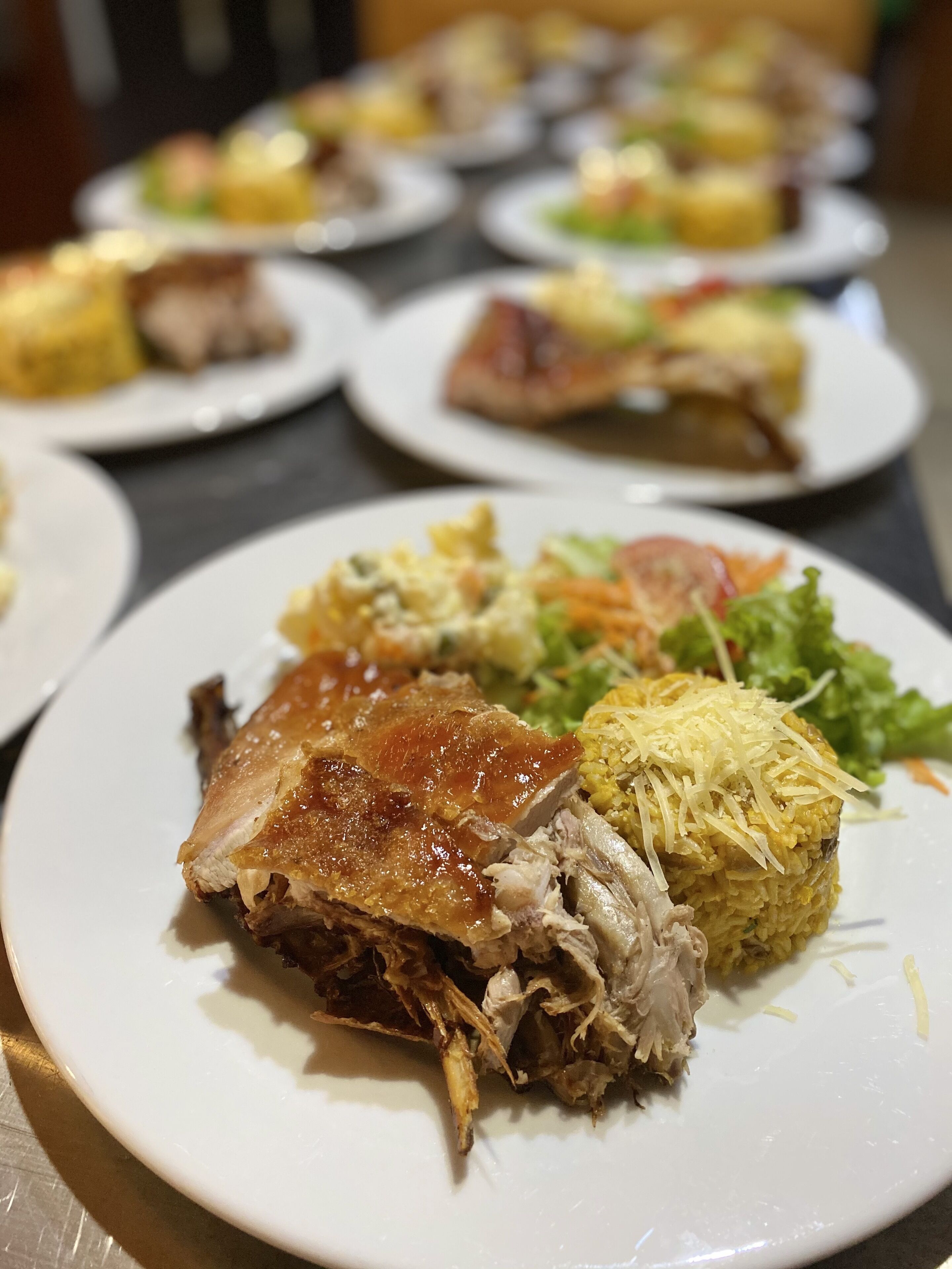 Una mesa con varios platos de comida, incluyendo un plato destacado con un muslo de pollo asado y acompañamiento de arroz.