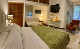 Habitación de hotel con cama, escritorio, silla, televisor y ventana con cortinas.
