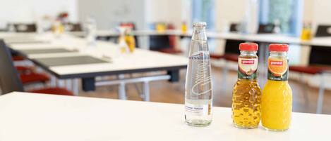 Un aula con mesas y sillas, una botella de agua y dos botellas de zumo de naranja Granini.