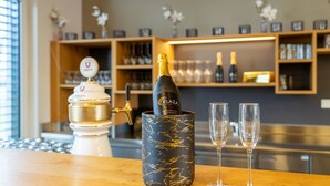 A bar area with a bottle of champagne in a decorative holder, two empty glasses, and a coffee machine. - PLAZA INN Dachau - München (Dachau)