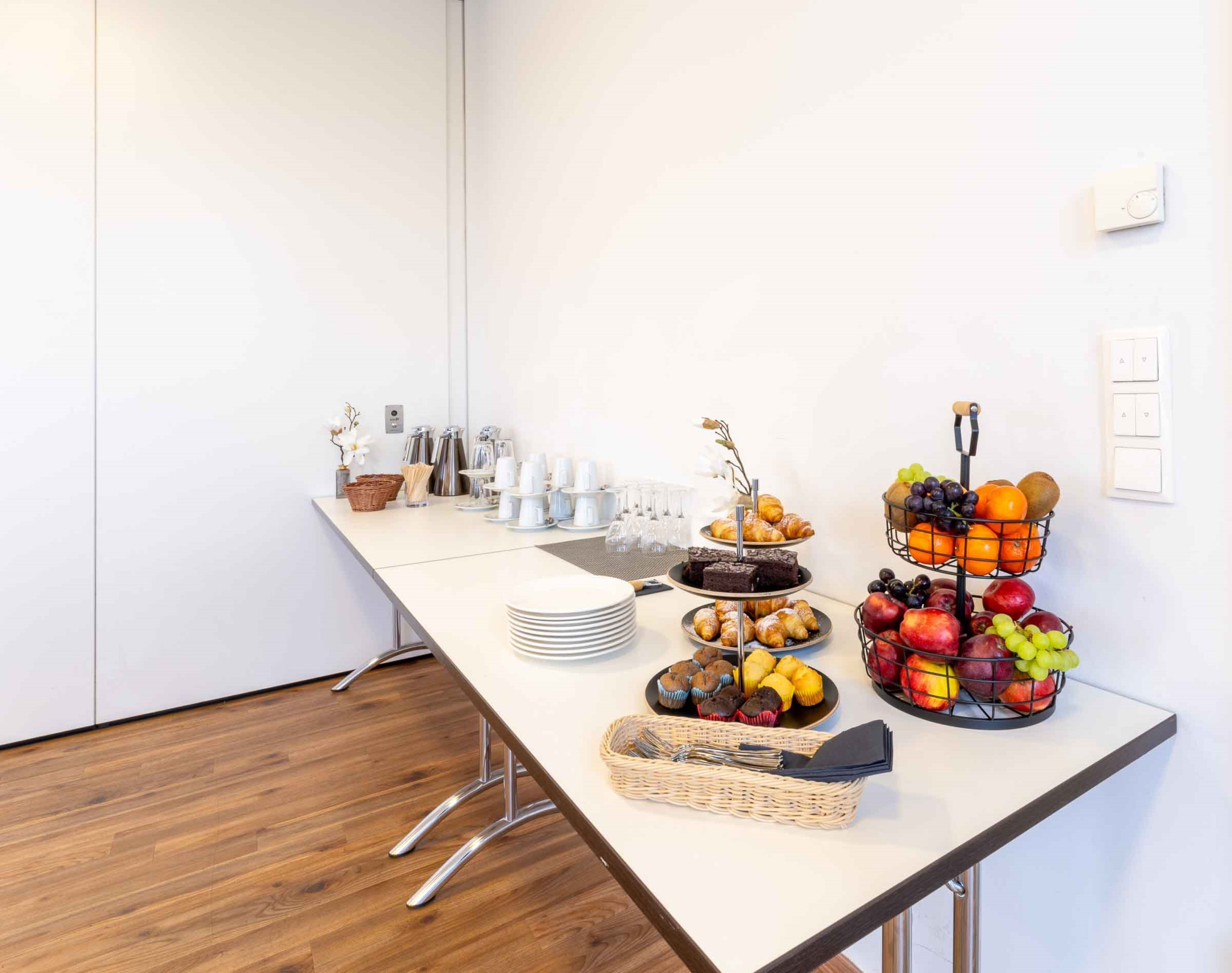 A buffet table with various food items, including pastries, fruits, and beverages.